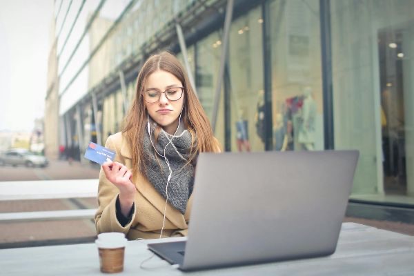 mulher com computador e cartão | Foto: Getty images